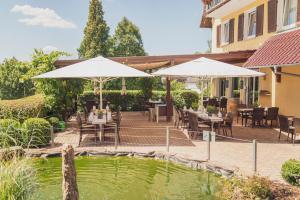 a patio with tables and umbrellas next to a pond at Hotel - Restaurant Sonneneck in Dornstetten