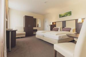a hotel room with two beds and a chair at Hotel - Restaurant Sonneneck in Dornstetten