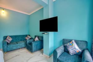 a living room with two blue couches and a flat screen tv at Candolim Beach White Residency in Baga