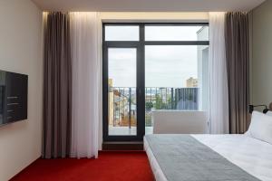 ein Hotelzimmer mit einem Bett und einem großen Fenster in der Unterkunft LEV Lifestyle Hotel - Maestro in Lwiw