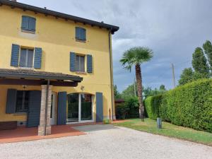 a yellow house with blue shutters and a palm tree at B&B QuattroL in Bastiglia