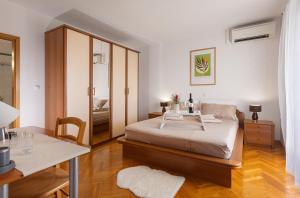 a bedroom with a bed and a table and a mirror at House Olive Garden Strunjan in Strunjan