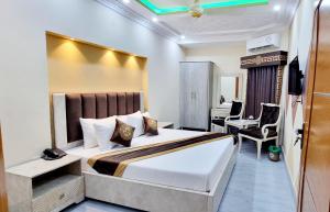 a hotel room with a bed and a desk at Al Warda Hotel in Lahore +17 photos