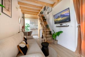 a living room with a couch and a tv on the wall at Jacuzzi Sauna privatif - La Cabanette Spa in Saint-Maur-des-Fossés