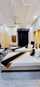two large beds in a room with chairs and tables at Al Warda Hotel in Lahore