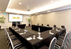 a conference room with tables and chairs and a screen at Sudima Auckland Airport in Auckland