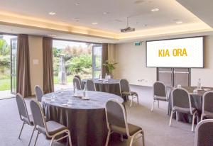 a conference room with tables and chairs and a screen at Sudima Auckland Airport in Auckland