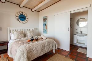 a bedroom with a bed and a clock on the wall at C'est la Vie in Paternoster