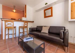 a living room with a leather couch and a table at Apartamentos Wundermar in Torredembarra