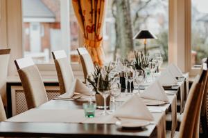 a dining room with tables and chairs with glasses and napkins at Hotel Hüttmann in Norddorf +127 photos