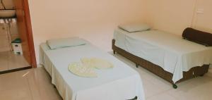 2 posti letto in una piccola stanza con lenzuola bianche di Hotel Cerrado Palace a Ribas do Rio Pardo