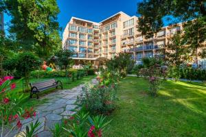 a park with a bench in front of a building at Hotel Riva Park - All Inclusive in Sunny Beach