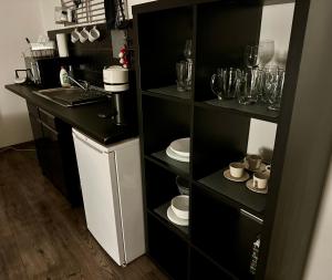 a kitchen with black shelves with glasses and dishes at Benvenuto Apartman in Budapest