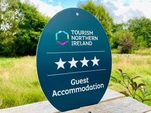 ein Schild mit der Aufschrift „Tourismus Nordirland“ und eine Gästeunterkunft in der Unterkunft Peatlands Retreat, Causeway Coast in Ballybogy