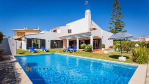 a villa with a swimming pool in front of a house at Greice Homes-650 meters from the beach, 4 bedrooms villa for holidays in Vilamoura-Quarteira in Quarteira