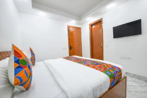 a bedroom with a bed with a television on the wall at FabExpress The Cozy Cloud in New Delhi