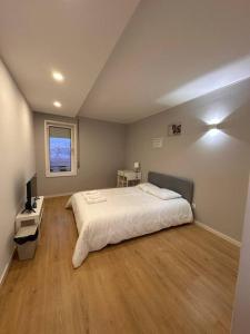 a bedroom with a white bed and a wooden floor at Pereira Azuara in Póvoa de Varzim