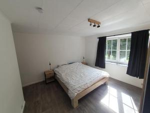 a white bedroom with a bed and a window at Douce Mathilde in Aywaille
