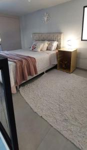 a bedroom with a bed with a rug and a night stand at Loft espaçoso e confortável in Três Marias