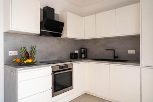 a white kitchen with white cabinets and a sink at Villa Full Moon Luxury Apartments Novalja in Novalja