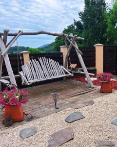 a wooden deck with a bench and some flowers at Rozprávkový domček blízko jazera in Štiavnické Bane