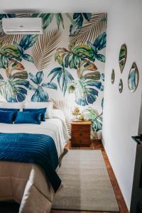 ein Schlafzimmer mit einem Bett mit tropischer Tapete in der Unterkunft Fantástica casa con piscina Carmona Sevilla in Brenes