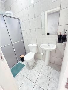 a white bathroom with a toilet and a sink at JK Central in Santa Cruz do Sul