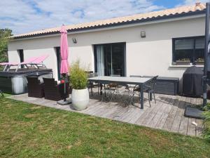 eine Terrasse mit einem Tisch, Stühlen und einem Grill in der Unterkunft Maison individuelle in Neuville-du-Poitou