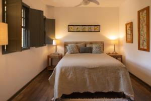 a bedroom with a large bed with two lamps at Chalés Cores da Mata in Tiradentes
