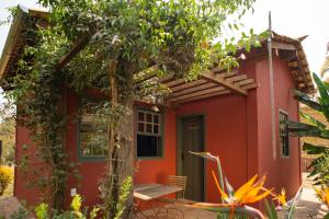 a small red house with a tree in front of it at Chalés Cores da Mata in Tiradentes