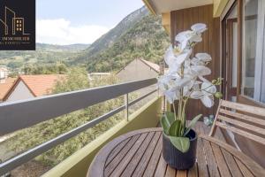a wooden table with a vase of flowers on a balcony at Appartement City Mountain in Cluses