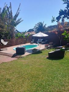 a swimming pool in a yard with an umbrella at Namorada Brava Guest House Praia Brava, Piscina & Naturaleza in Búzios