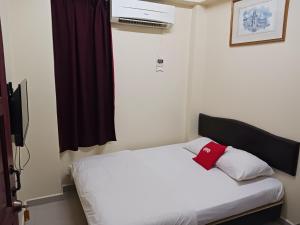 a bedroom with a white bed with a red pillow at Casavilla Hotel in Taiping