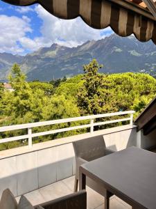 een tafel en stoelen op een balkon met uitzicht op de bergen bij Penthousetraum im Herzen Merans in Merano