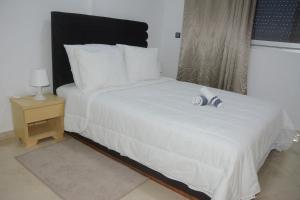 a bedroom with a white bed and a night stand at Town Hotel in Kenitra