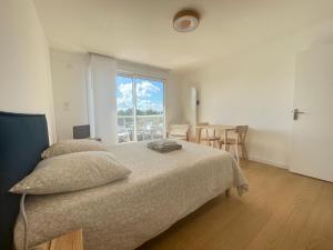 een slaapkamer met een bed en een tafel met stoelen bij Studio - balcon - bord de mer in Courseulles-sur-Mer