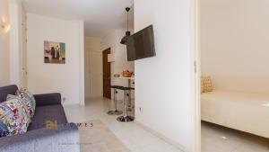 a living room with a couch and a tv on a wall at GREICE HOMES 1 BEDROOM APARTMENT CENTRE OF VILAMOURA in Vilamoura
