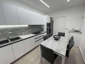 a kitchen with white cabinets and a table with chairs at Camera Aurora Legnago in Legnago
