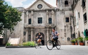 two people riding bikes in front of a building at Mad Monkey Manila in Manila