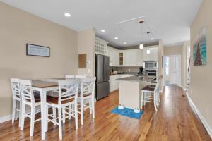 a kitchen with white cabinets and a table and chairs at Pelican Pleasure by Sea Scape Properties in Carolina Beach