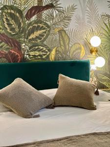 a bed with two pillows and a wall with plants at Golden Palm B&B in Bari +19 photos