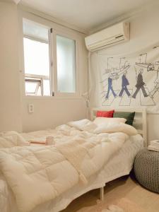 a bedroom with a large white bed and a window at Gurum Stay in Suwon