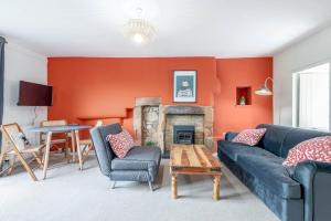 a living room with a blue couch and a fireplace at The Cooperage Garden Apartment - Crail in Crail