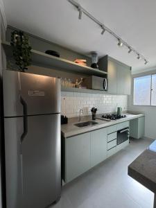 a kitchen with a stainless steel refrigerator and white cabinets at Modern apartment near SESC in Franca +16 photos