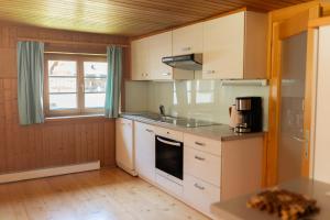 a kitchen with white cabinets and a sink and a window at Haus OmaGermana in Schoppernau