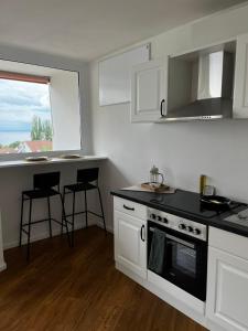 a kitchen with white cabinets and a stove top oven at Ferienwohnung Emilio in Überlingen +7 photos