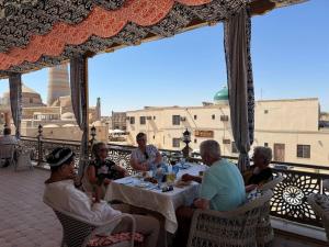 a group of people sitting around a table on a balcony at Khiva Minor in Khiva