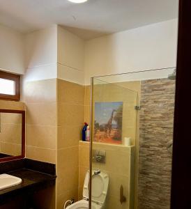 een badkamer met toilet en een schilderij van een giraffe bij Golden Sun Studio Apartment in Ukunda