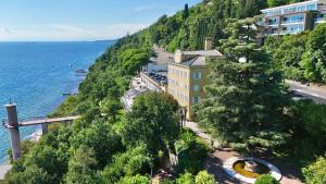 a building on a hill next to the ocean at Hotel Riviera & Maximilian's in Trieste