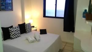 a bedroom with a white bed with pillows and a window at Natal Prime Apartments -Porto Imperial in Natal +86 photos